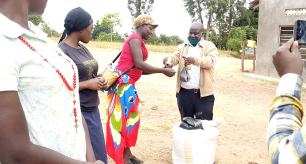 LC III chairperson Mr. Sowedi handing over IGA input for back yard gardening to AGYW to strengthen their income from Kibinge s/c head quarters on 18/07/2020